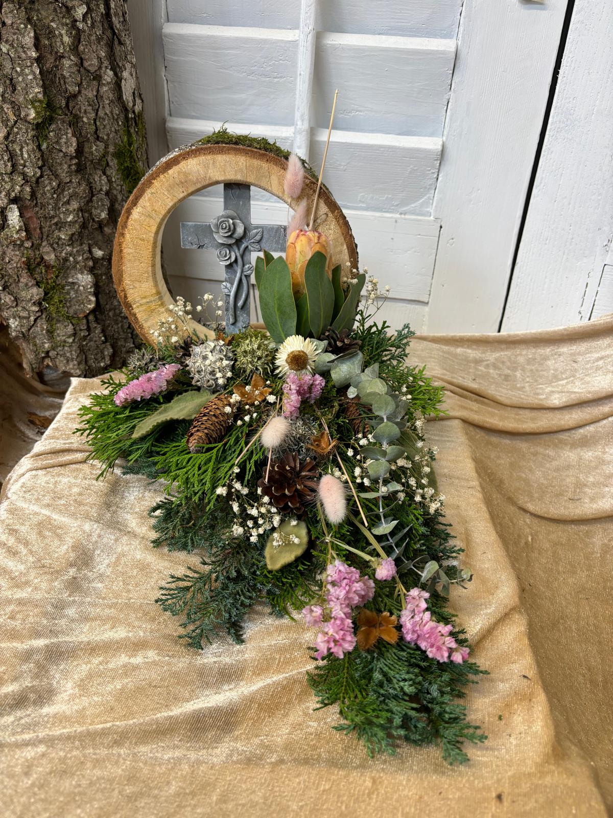 Grabschmuck mit Tannengrün, Zapfen, rosa Blüten und einer Laterne