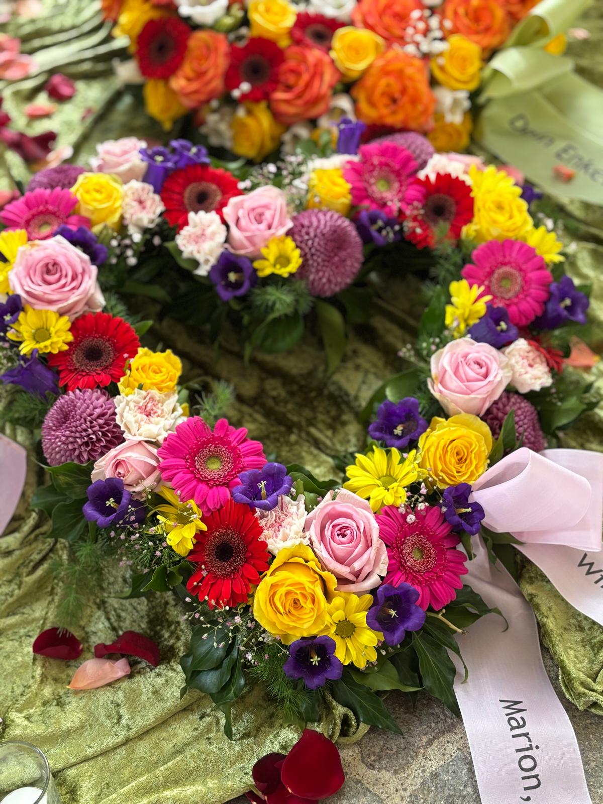 Trauerkranz mit pinken, gelben, weißen und orangefarbenen Blüten