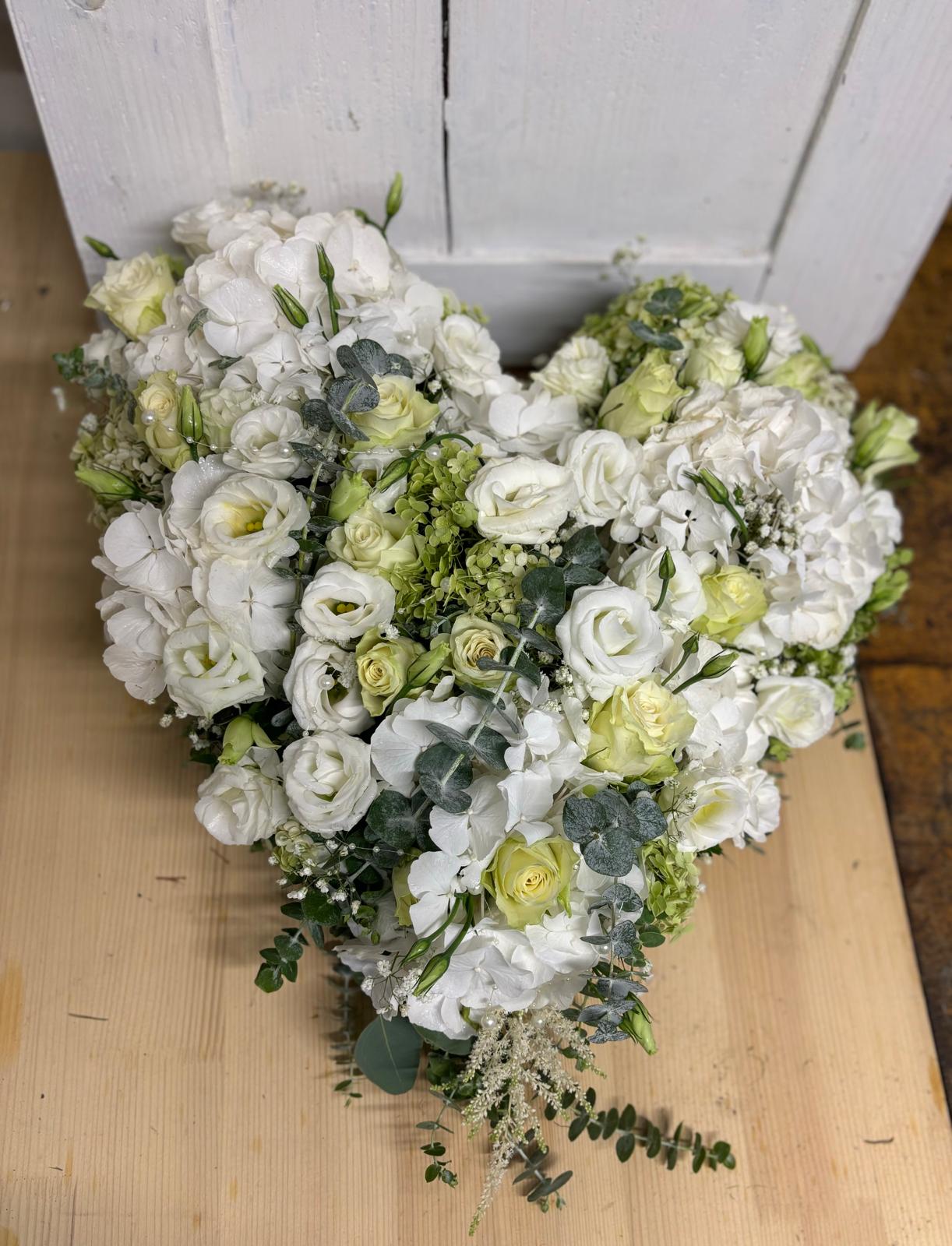 Herzförmiger Autoschmuck aus weißen Blüten und frischem Grün